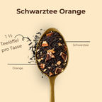 Schwarztee Süße Orange lose auf einem Messinglöffel mit Schwarztee und Orangenstücken, Dosierung 1 ½ Teelöffel pro Tasse